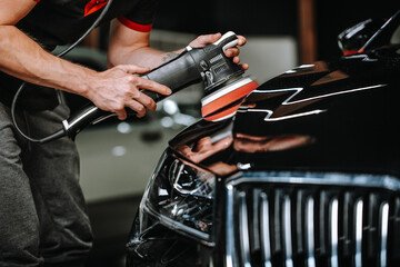 Technician machine-polishing a car panel to remove swirl marks and restore gloss before coating
